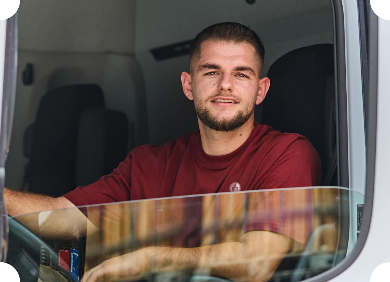 Fahrer sitzt in einem Lieferwagen und schaut in die Kamera