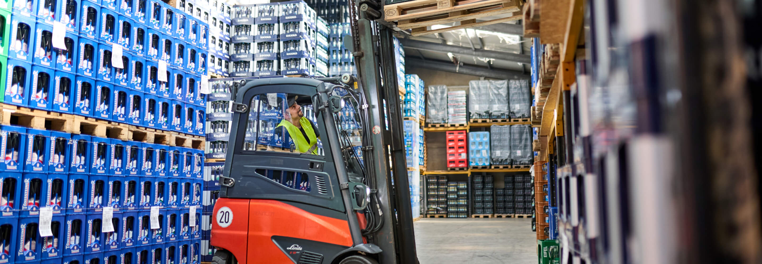 Gabelstaplerfahrer transportiert Getränkekisten im Lager