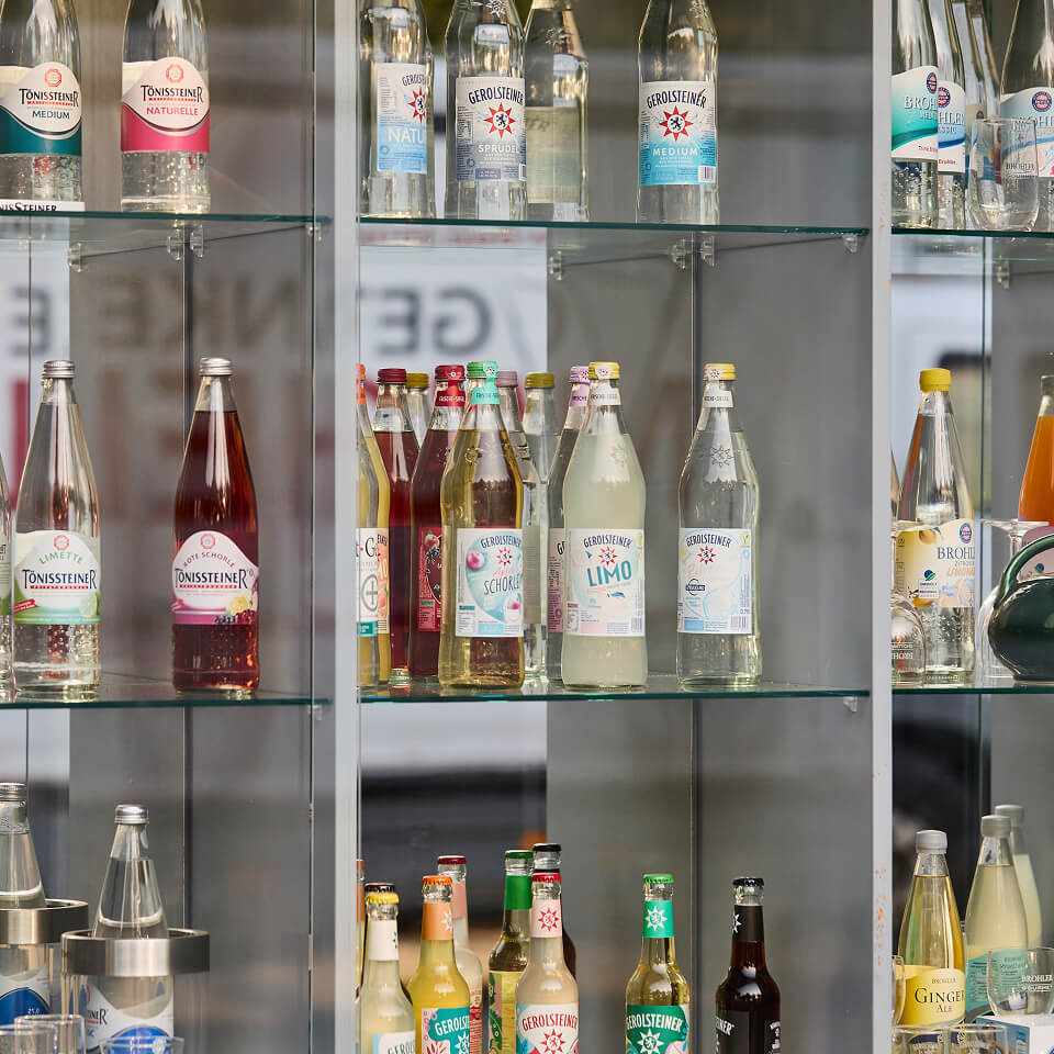 Getränkeflaschen unterschiedlicher Marken in einer Glasvitrine