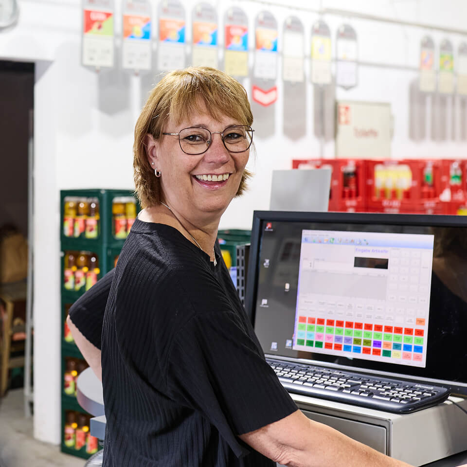 Mitarbeiterin arbeitet an einer Kasse im Getränkemarkt