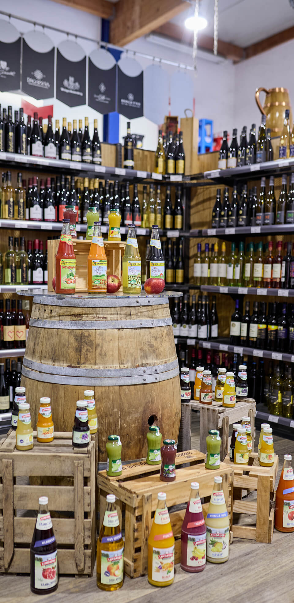 Sortiment aus Saft- und Limonadenflaschen auf einem Holzfass präsentiert