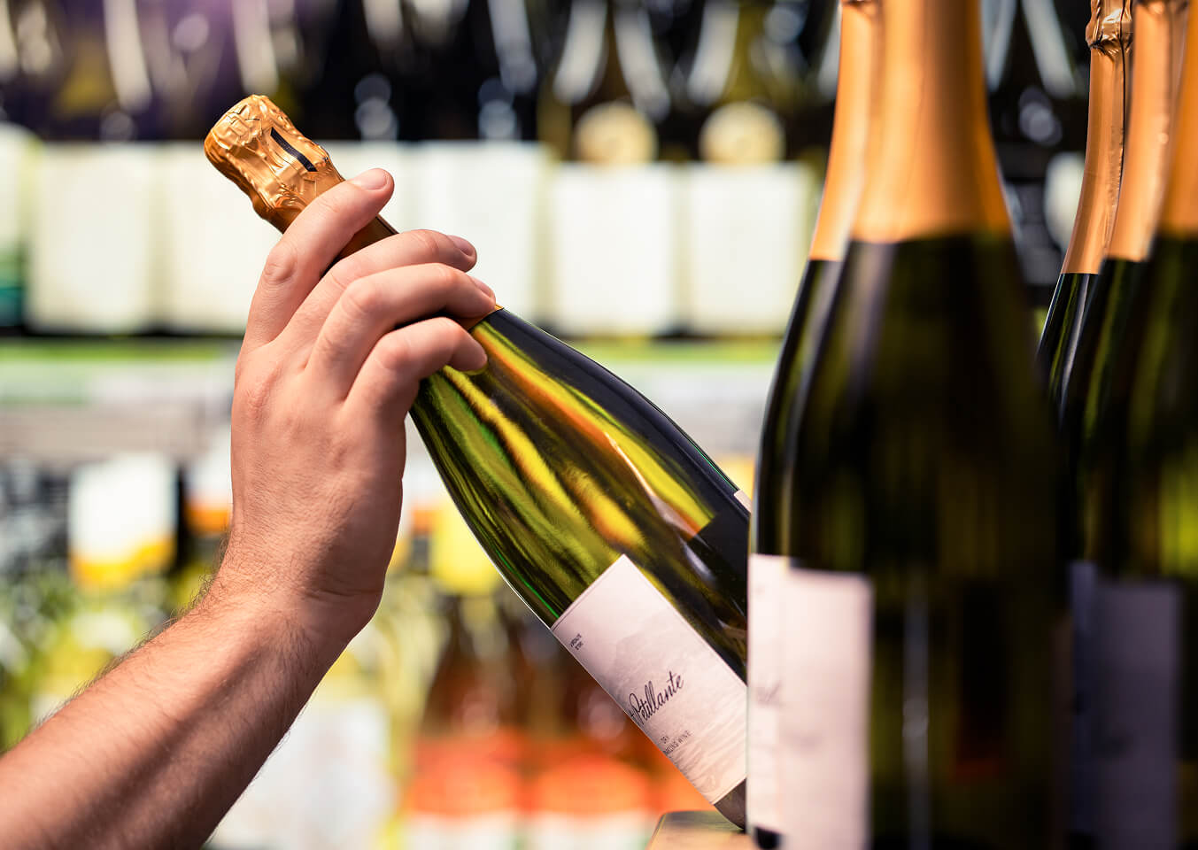 Hand hebt eine Sektflasche im Getränkefachhandel