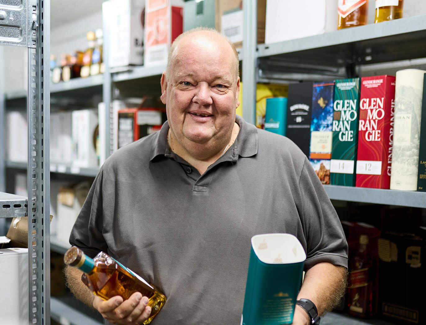 Mitarbeiter hält eine Whiskyflasche im Lager in der Hand