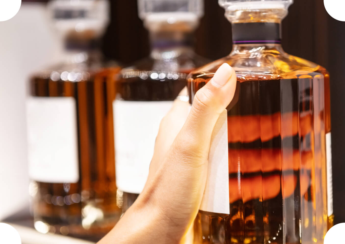 Hand greift nach einer Whiskyflasche im Spirituosenregal