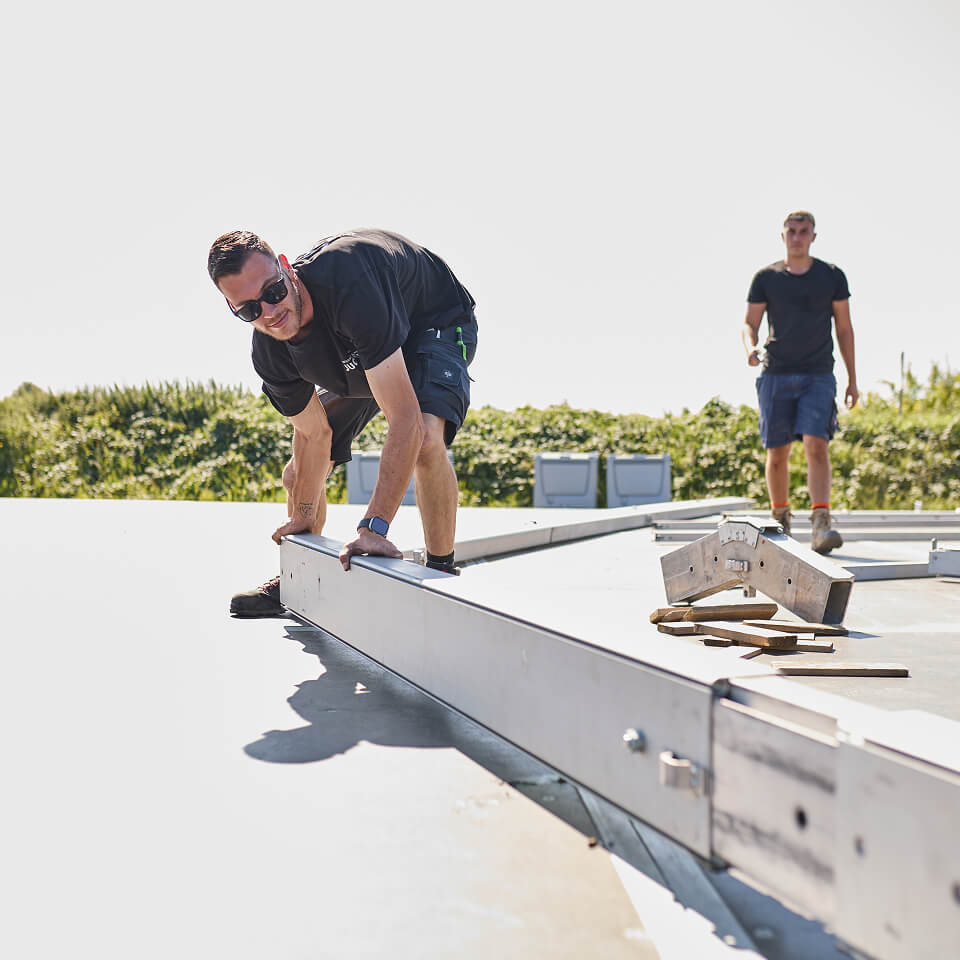 Zwei Mitarbeiter arbeiten gemeinsam an einem Zeltgerüst